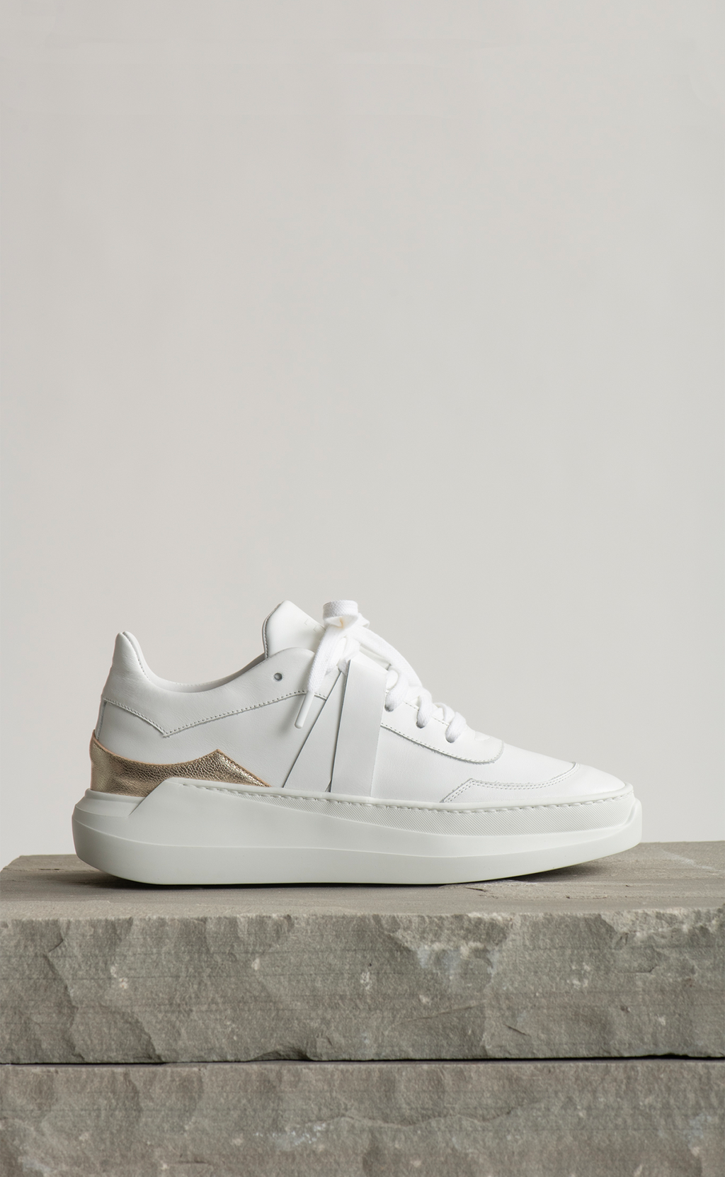 EVI G1 Or Polaire – white leather sneaker Made in France with metallic gold heel detail, side view on stone block